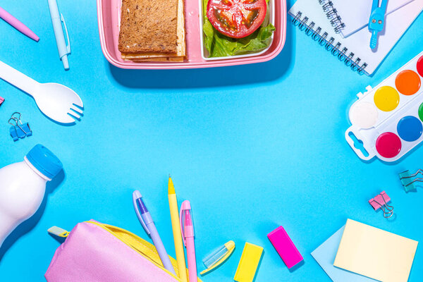 Healthy school meal, back to school concept. Children packed lunch box with balanced diet snack food - yogurt, cereal toast sandwich, apple, fresh vegetable salad, high-colored bright background