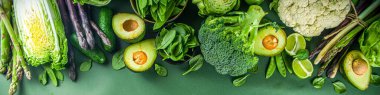 Sağlıklı diyet bahar yemekleri. Taze çiğ organik sebze çeşitleri - brokoli, karnabahar, kabak, salatalık, kuşkonmaz, ıspanak, avokado, koyu yeşil arka planda lahana.