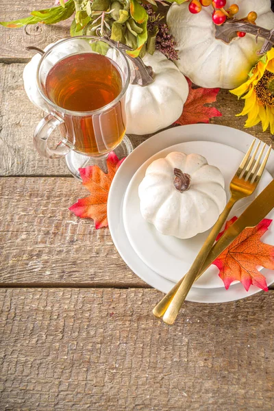 Thanksgiving Food concept. Autumn Table Setting with Plate, Tea cup, pumpkins, Sunflower and Warm Plaid or Sweater, comfort and cozy brick wood home background copy space