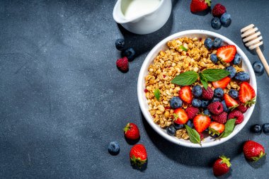 Healthy breakfast granola with fresh berry - strawberry, raspberry, blueberry on black background