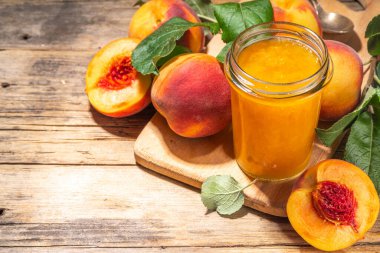 Red peach jam in small jar. Homemade autumn peach jam with fresh fruits. Fall preparations and canning on wooden table background copy space