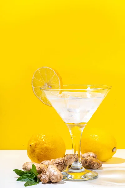 Ginger lemon martini. Sour tasty alcohol cocktail on white and yellow trendy background copy space