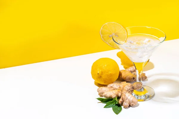 Ginger lemon martini. Sour tasty alcohol cocktail on white and yellow trendy background copy space