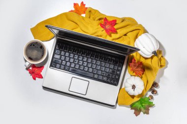 Cozy fall background with coffee cup, tablet notebook, ear-pods, white, orange pumpkins, autumn leaves decor on white home office table background. Autumn still life composition flatlay