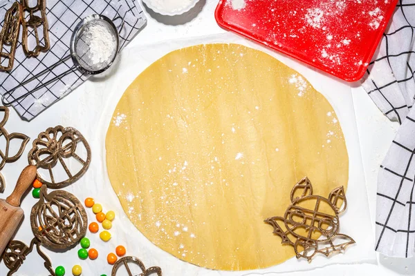 Halloween cooking baking background.  Making cookies for Halloween party treats on white kitchen table, with Halloween symbols cookie cutters, baking utensils and ingredients top view