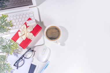 İş yerindeki gizli Noel Baba 'dan hediye. Ofis Noel ve Yeni Yıl kutlama oyunu. Ofis masası yüzeyi, neşeli hediye kutusu olan defter, beyaz arkaplan düz kopya alanı