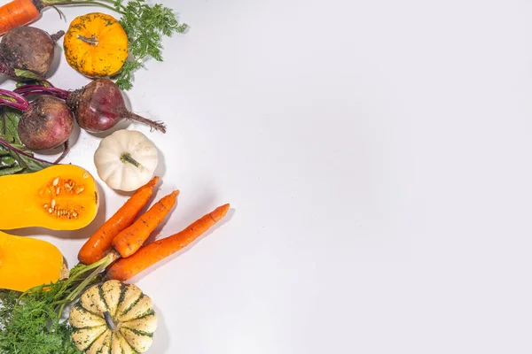 Autumn cooking, organic farm food background. Harvesting concept. Cutting board with fresh vegetables colorful pumpkins, squash, beetroot, carrots, cabbage, on a white marble table. cooking background