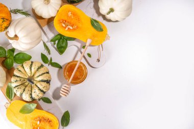 Bal kabakları değişik boyutlarda, çeşitli boyut ve renklerde kabaklar, bitki ve baharatlar, zeytin yağı, bal, beyaz mutfak masası arka planında üst görünümde fotokopi alanı 