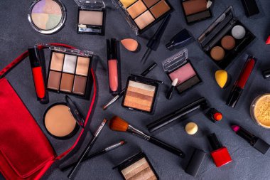 Sonbahar makyaj seti, sonbahar yaprakları ve güzellik aksesuarları ile siyah masa arka planında. Beyaz masa arkasında çeşitli makyaj malzemeleri, sonbahar süveteri ve kadın çantası.