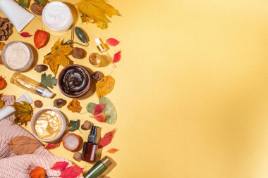 Çeşitli besleyici nemlendirici yaşlanma önleyici sonbahar yüz bakımını ayarlayın. Serum şişesi, krem, fırça, organik güzellik bakımı sonbahar yaprakları, dekor, sıcak süveter, altın sarısı arka planda