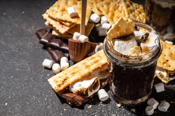 Dark chocolate Smores mug cake dessert, quick simple recipe baking in microwave, lava cake, brownie with marshmallows and graham crackers in a glass