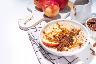 Basit bir sonbahar geleneksel Amerikan kahvaltısı. Elmalı yulaflı yulaf lapası, elmalı, cevizli ve karamelli beyaz masa arkası fotokopi masası.