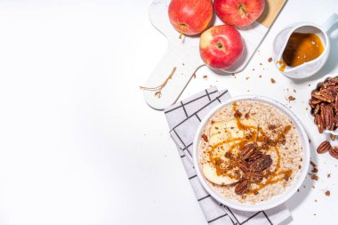Basit bir sonbahar geleneksel Amerikan kahvaltısı. Elmalı yulaflı yulaf lapası, elmalı, cevizli ve karamelli beyaz masa arkası fotokopi masası.