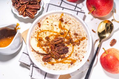 Basit bir sonbahar geleneksel Amerikan kahvaltısı. Elmalı yulaflı yulaf lapası, elmalı, cevizli ve karamelli beyaz masa arkası fotokopi masası.
