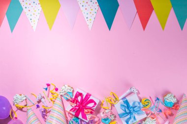 Mutlu yıllar tebrik kartı geçmişi. Renkli tatil aletleri olan düz yatak - doğum günü partisi şapkaları, şişirme makineleri, hediye kutuları, balonlar, buharlı mumlar, pembe arka plan fotokopi alanı