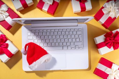 Noel indirimi, tatil hazırlıkları. Noel Baba 'nın elleri dizüstü bilgisayarlı, sıcak çikolatalı latte bardağı, hediye kutuları, altın arka planda yatıyordu. Dilek listesi yapıyorum, Noel için hazırlık hediyeleri hazırlıyorum..
