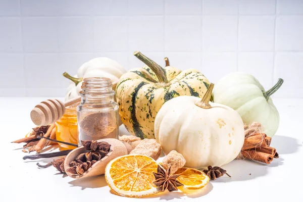 Autumn fall pumpkin spice baking and drink ingredients. Various colorful pumpkins, nuts, seasonal spices on white background. Cooking pumpkin pie, latte, cookies for autumn Thanksgiving  holidays