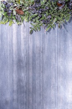 Klasik basit bir Noel tebrik kartı geçmişi. Yılbaşı ağacı ve kış meyvesi dalları eski gri ahşap arka planda. Üst görünüm kopya alanı