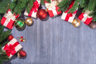 Tahta zemin üzerinde Noel ağacı olan hediye kutuları. Çeşitli kırmızı ve beyaz hediyeler, şenlikli kurdele, köknar ağacı dalları ve eski gri kereste ahşap arka planda Xmas süslemeleri, fotokopi alanı