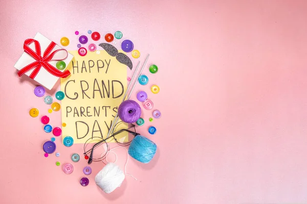 Happy Grandparents day greeting card background. Granny and grandpa\'s day celebration, with gift boxes, knitting threads, buttons, glasses, decor top view copy space