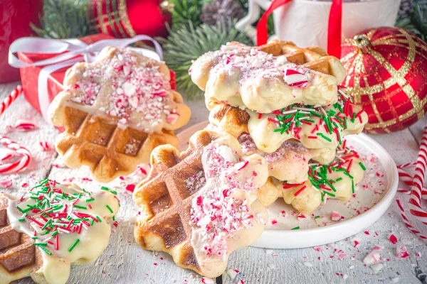 Stack of homemade Belgian waffles for Christmas breakfast. Traditional waffles dipped in white chocolate, with Candy Cane crumbs and festive sugar sprinkles