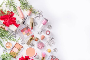 Kış ve Noel dekoratif makyaj malzemeleri, yapay kar taneleri, Noel ağacı dalları, hediye kutuları, güzellik aksesuarları. Noel ve Yeni Yıl kış kozmetik ürünleri satışı bembeyaz arka planda duruyordu