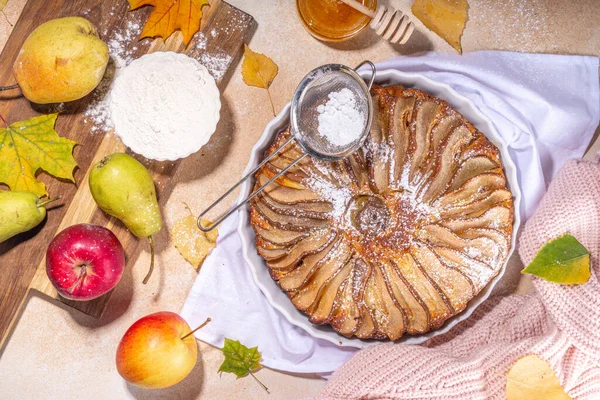 Homemade pear pie, sponge cake with sliced pear, cinnamon and honey, with fresh pears on beige stone background top view copy space
