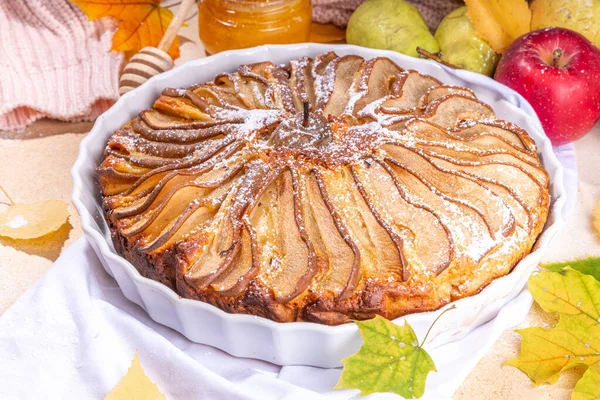 Homemade pear pie, sponge cake with sliced pear, cinnamon and honey, with fresh pears on beige stone background top view copy space