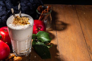 Ev yapımı elmalı turta milkshake, tart parçacıkları ve baharatlı kırmızı sonbahar elma proteini smoothie, sıcacık ahşap arka planda mevsimlik sağlıklı bir kahvaltı içeceği.