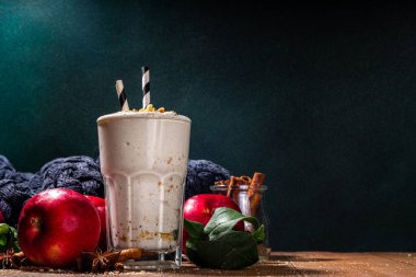Ev yapımı elmalı turta milkshake, tart parçacıkları ve baharatlı kırmızı sonbahar elma proteini smoothie, sıcacık ahşap arka planda mevsimlik sağlıklı bir kahvaltı içeceği.