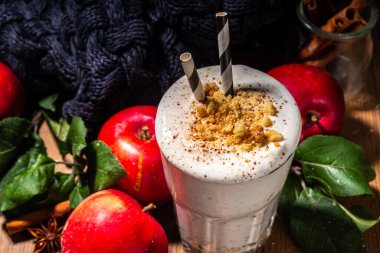 Ev yapımı elmalı turta milkshake, tart parçacıkları ve baharatlı kırmızı sonbahar elma proteini smoothie, sıcacık ahşap arka planda mevsimlik sağlıklı bir kahvaltı içeceği.