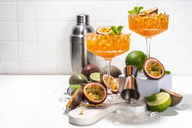 Tutkulu meyve martini kokteyli. Tatlı porno yıldızı alkollü içecek. Taze tutku meyvesi ve limon. Bar aletleri de yer kaplıyor.