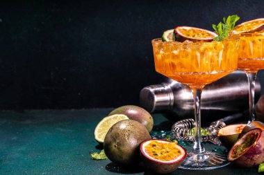 Tutkulu meyve martini kokteyli. Tatlı porno yıldızı alkollü içecek. Taze tutku meyvesi ve limon. Bar aletleri de yer kaplıyor.