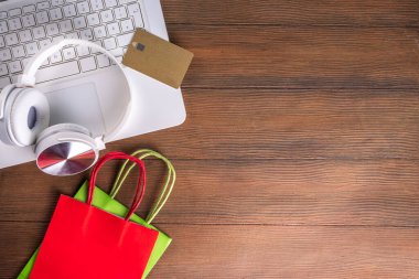 İnternetten Noel alışverişi yapıyorum. Kış Xmas çevrimiçi satışı. Kulaklıklı beyaz laptop, alışveriş arabası ve çantalar, kredi kartı ahşap arka plan kopyalama alanı