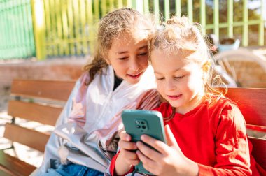 İki mutlu çocuk. Kızın elinde akıllı telefon var..