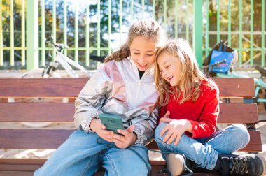 İki mutlu çocuk. Kızın elinde akıllı telefon var..