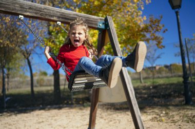Küçük çocuk uçan sandalyede sallanıyor.