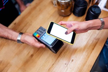 Bir restoranın barındaki kablosuz ödeme terminalinde müşterinin elinde akıllı bir telefon tutmasının ayrıntıları..