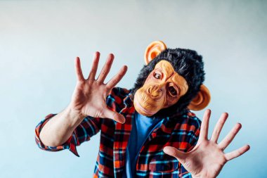 Maymun maskeli adam el kol hareketi yapıyor..