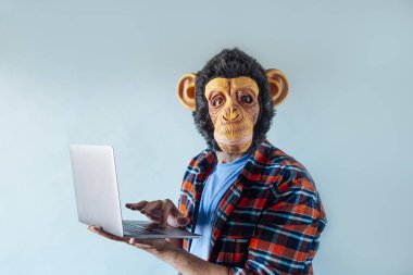 Maymun maskesi takan ve dizüstü bilgisayar kullanan adam..