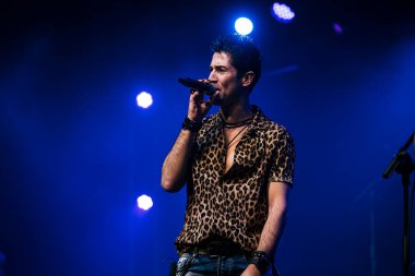 Canlı bir konserde seyircilerin önünde şarkı söyleyen sanatçı.