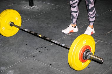 Kadın atlet ayakları antrenman için halter hazırlıyor.