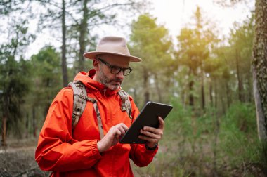 Ormanda tablet kullanan bir adam.