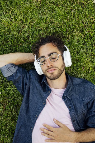 Bahçede kulaklıklarla yatan yakışıklı genç bir hippi portresi..