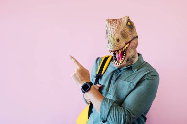Pembe arka planda kertenkele maskeli adam yan tarafı işaret ediyor..