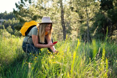 Biyolog kadın sahada akıllı telefonuyla fotoğraf çekiyor..