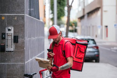 Eve kuryeyle yemek getiren adam akıllı telefona danışıyor..