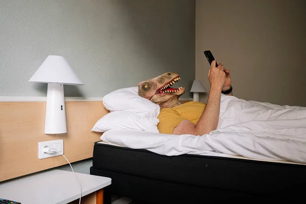 Άνθρωπος Μάσκα Σαύρας Χρησιμοποιώντας Smartphone Ένα Κρεβάτι Ξενοδοχείου — Φωτογραφία Αρχείου