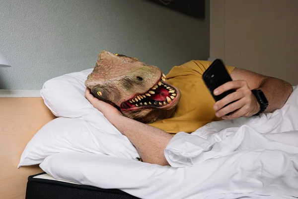 Άνθρωπος Μάσκα Σαύρας Χρησιμοποιώντας Smartphone Ένα Κρεβάτι Ξενοδοχείου — Φωτογραφία Αρχείου