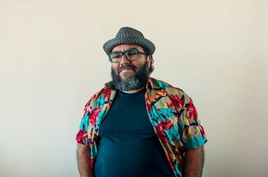 Sakallı ve şapkalı şişman adam kameraya bakıyor..